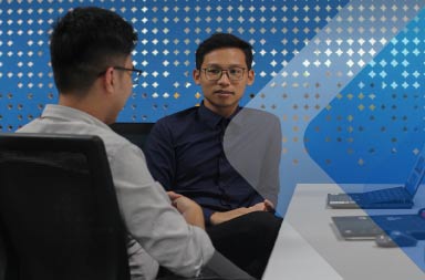 Two men in an office to illustrate an article on hiring international employees. By Phyo Min on Unsplash.