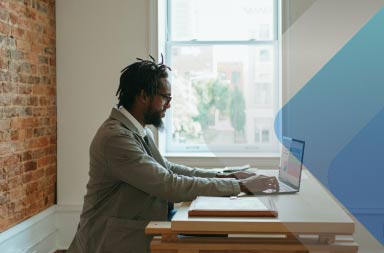 Man using computer by a window to illustrate article on distributed workforce management