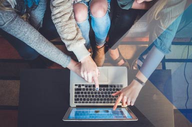 People working together on a computer to illustrate article on global talent acquisition strategy. Photo by John Schnobrich on Unsplash.