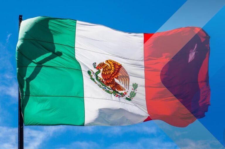 Mexican flag flying in wind to illustrate article on headhunters in Mexico. Photo by Alexander Schimmmeck on Unsplash