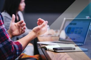 Person at computer with phone to illustrate article on digital networking. Photo by Headway on Unsplash.