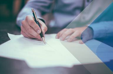 A man signing paper to illustrate article on international recruitment and staff selection. By Scott Graham on Unsplash.