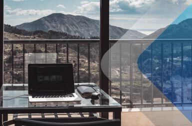Um computador numa secretária com uma vista fantástica para ilustrar um artigo sobre como ultrapassar os desafios de comunicação em equipe remota Por Euan Cameron em Unsplash