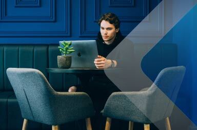 Man working at table in blue room to illustrate article on hiring independent contractors. By Stefan Stefancik on Unsplash.