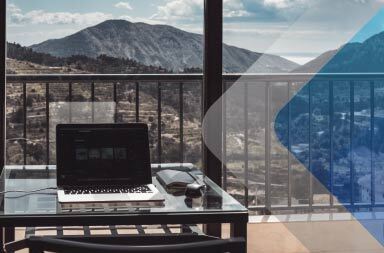 A laptop at a desk looking out onto a mountain range to illustrate the challenges of managing a global workforce. By Euan Cameron on Unsplash.