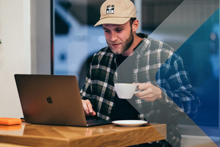 Man drinking coffee at laptop to illustrate ease of hiring overseas contractors. By Kal Visuals on Unsplash.
