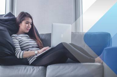 Woman on sofa with computer to illustrate article on hiring foreign international contractors. By Mimi Thian on Unsplash.